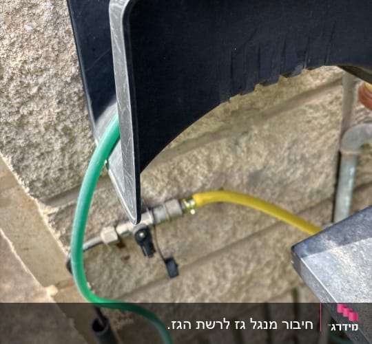 צינור ירוק וצהוב מחובר לקיר עם מתקן פלסטיק